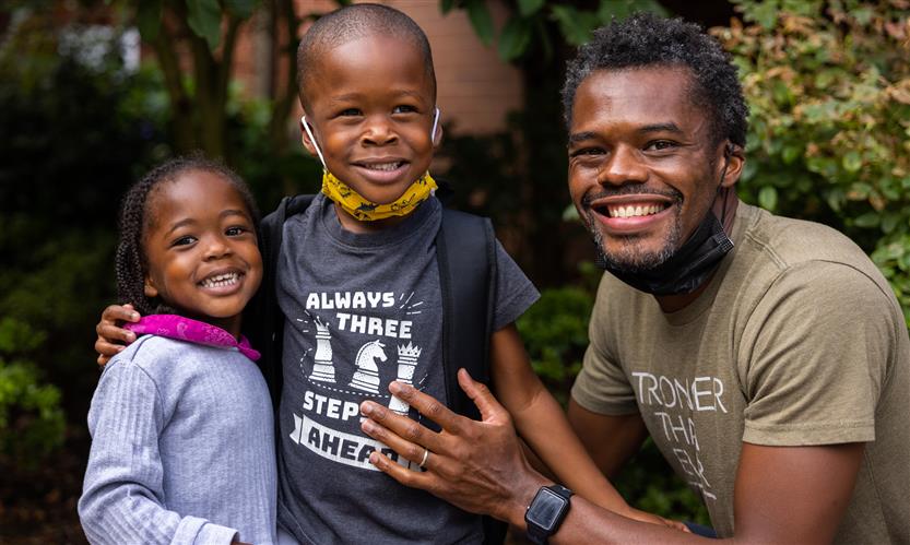A father and two children smile